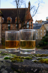 Scotch single malts or blended whisky spirits in glasses with old houses of Edinburgh on background, Scotland, UK