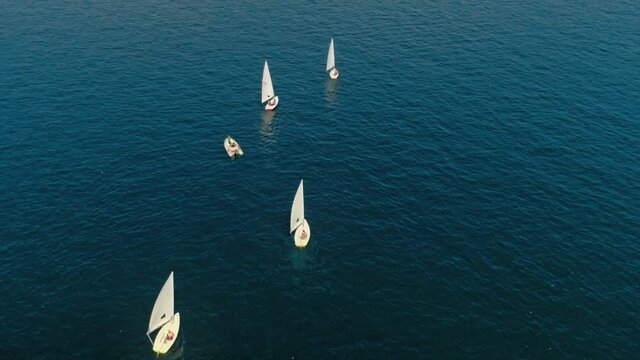 Sailing school for kids or adults with small sail boats or yachts drifting in blue ocean, sea or lake waters. Sail trip in summer on mediterranean sea. European vacation in open water on private yacht
