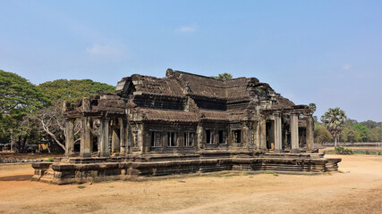 Obraz premium Angkor Wat library building. Sunny summer day. The ruins of an ancient stone unique cruciform building. Well preserved columns at the entrances, window openings, roof. UNESCO Heritage. Cambodia.