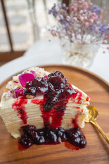 Crepes cake with blueberry sauces on wooden plate