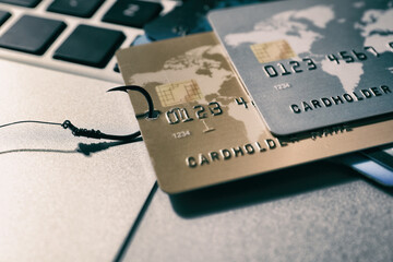 Fishing hook with credit cards on laptop, closeup. Cyber crime