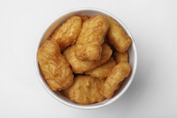 Bucket with tasty chicken nuggets on white background, top view