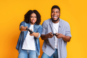 Young black couple with joysticks competing in video games with each other © Prostock-studio