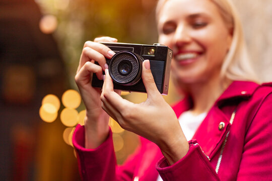 Cheerful woman taking photo with retro camera