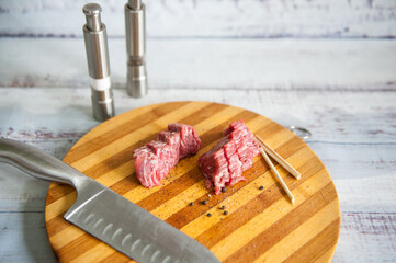Fresh raw beef meat slices on wooden cut board with knife and spices