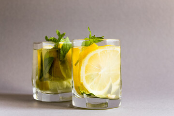 Detox water with mint, lemon on grey background. Citrus lemonade. Summer fruit infused water. Refreshing homemade cocktail