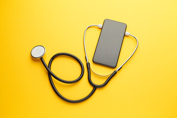Fototapeta na wymiar Smartphone and stethoscope on yellow background. Online medicine (telemedicine) technology. Service for remote diagnostic, chat with doctor.