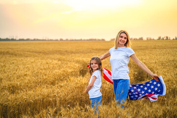 Mother and daughter with American Flag in a beautiful wheat field