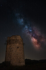 Bella vista de la Vía Láctea al lado de una antigua torre militar cristiana en España, en una noche oscura de verano