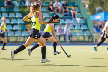 Fototapeta premium Young women playing field hockey game on the pitch