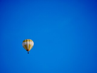balloon flying mid-air in sunshine against blue sky