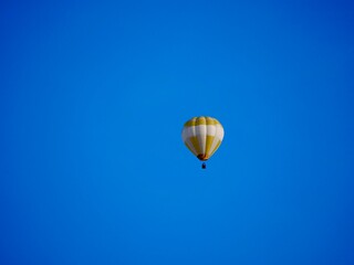 balloon flying mid-air in sunshine against blue sky