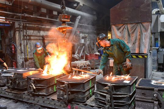 workers in a foundry casting a metal workpiece - safety at work and teamwork
