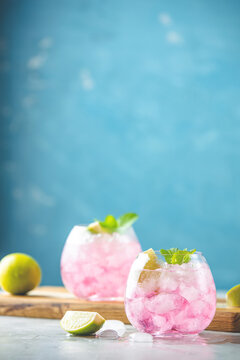 Pink cocktail with lime, crushed ice and mint on the light background, selective focus image, copy spice for you text, summer vacation and party concept.