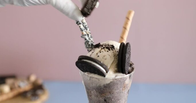 Decorating parfait with Oreo cookies and ice cream and biscuits