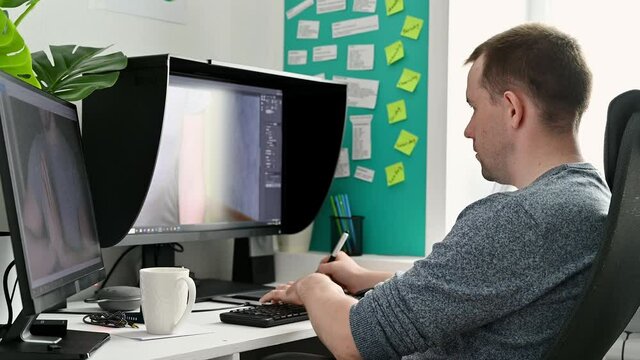 Work from home. Young male photographer processes photos on a computer at home.