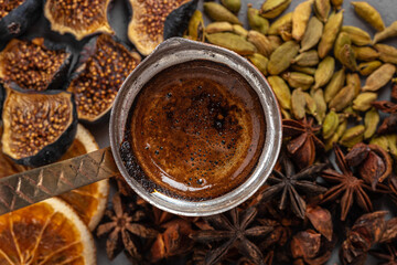 Copper coffee turk with dried seeds and fruits on grey surface