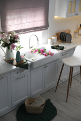 Beautiful kitchen interior with stylish furniture and fresh peonies