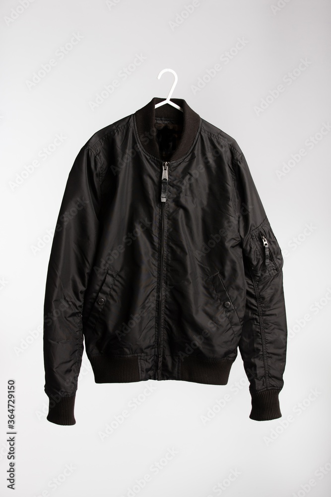 Poster Black jacket on cloth hanger with white wall in the background