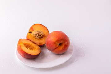 Nectarine peaches with a slice and leaves on a white background.
