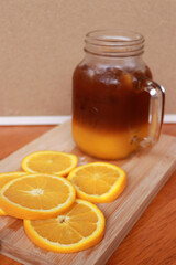 Orange slice and orange juice in a glass place on a wooden chopping block.