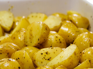 Macro close-up of sliced potatoes seasoned with herbs and olive oil
