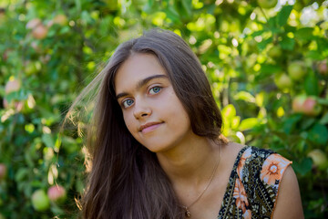Naklejka premium Portrait of a beautiful smiling girl. Summer girl closeup. Smiling girl with long hair. Portrait of a girl with long hair in the summer garden 