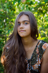 Fototapeta premium Portrait of a beautiful smiling girl. Summer girl closeup. Smiling girl with long hair. Portrait of a girl with long hair in the summer garden 