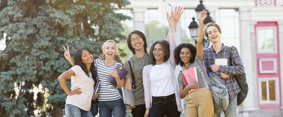 Cheerful students standing and waving outdoors.