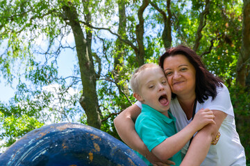 Happy mother and son with down syndrome hugged together in the park.