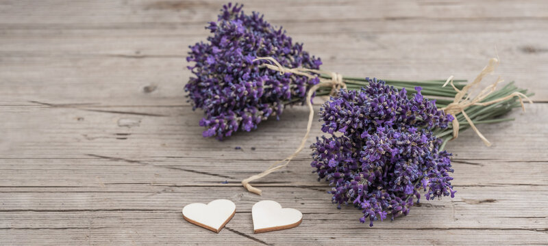 Many bouguet of violet purple lavendula lavender flowers herbs on old rustic wooden table with wooden hearts, wood background, close up