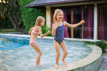 Little girls running in the swimming pool. Sisters playing together. Summer concept. Family activities. Happy childhood. Vacation in Asia.