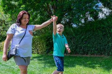 Obraz premium Happy mother and son with down syndrome they walk together in the park.