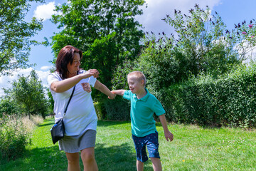 Happy mother and son with down syndrome they walk together in the park.
