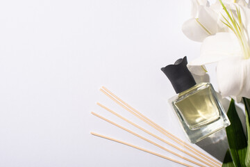 top view of aroma sticks with perfume in bottle near lilies on white background