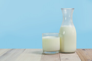 A bottle of rustic milk and glass of milk on a wooden table