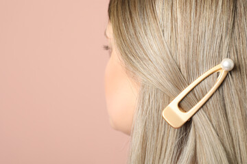 Young woman with beautiful hair clip on pink background, closeup