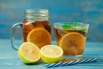 Iced tea with lemon slices and mint on wood background