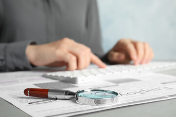 Woman at table, focus on magnifying glass. Job search concept