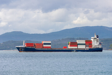 industrial cargo ship with multi-colored containers in sea strait