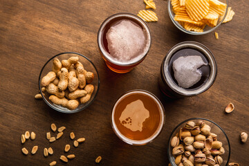 Meeting with friends at weekend in pub. Dark, light, unfiltered beer in glasses on table with snacks in plates