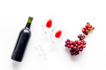 Red wine with grape - in glasses and bottle - on white desk top view