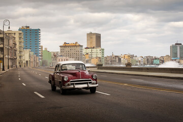 Old car on Malecon street of Havana with storm clouds in background. Cuba