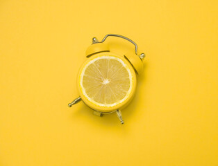 alarm clock with lemon slice  on a yellow  background,summer bright poster