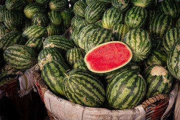 Red ripe sweet green watermelon cut in half on a pile of ripe watermelons. A red cut large watermelon in market.