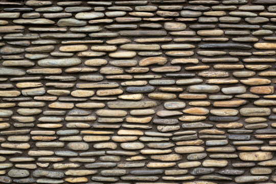 The wall made of yellow round stones. Walls made of pebbles, images for background
