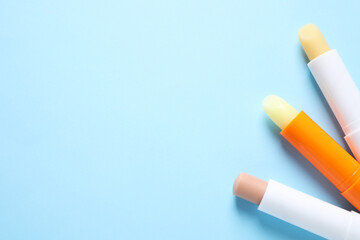 Hygienic lipsticks on light blue background, flat lay. Space for text