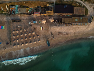 Aerial view of amazing beach with umbrellas and turquoise sea at sunrise. Black Sea at Vama Veche, Romania