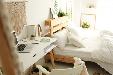 Stylish room interior with workplace and bed