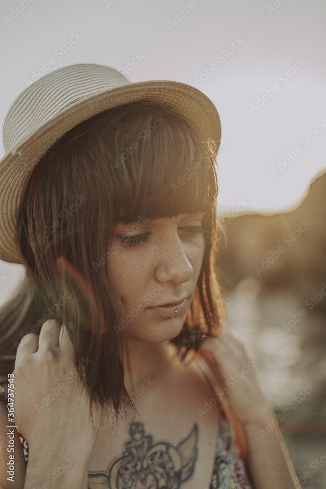 Sticker Closeup of a young caucasian female with tattoos wearing a dress and straw hat